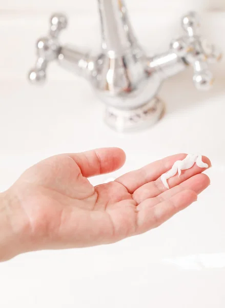 Hand mit Creme im Badezimmer — Stockfoto
