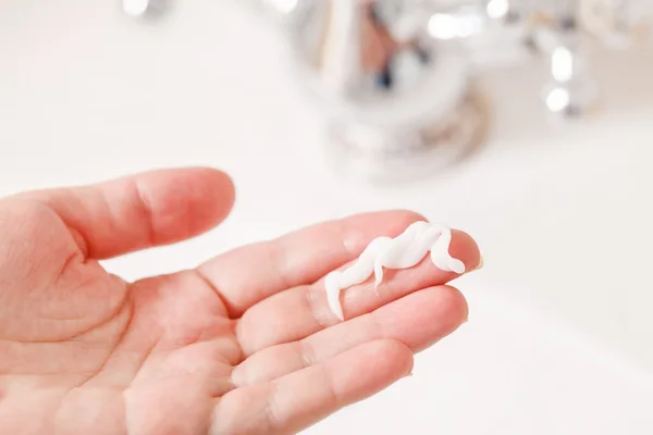 Hand with cream in bathroom — Stock Photo, Image