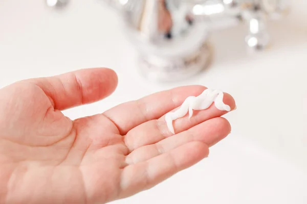 Hand with cream in bathroom — Stock Photo, Image