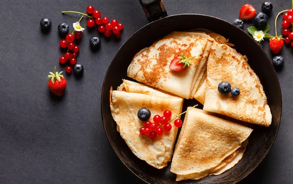 Pancakes with berries in pan — Stock Photo, Image