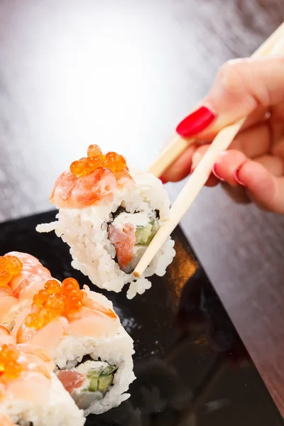 Hand with chopsticks takes sushi — Stock Photo, Image