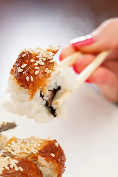 Hand with chopsticks takes sushi — Stock Photo, Image