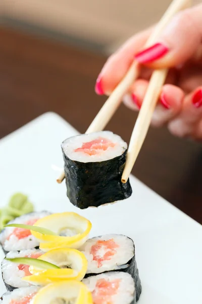 Main avec des baguettes prend sushi — Photo