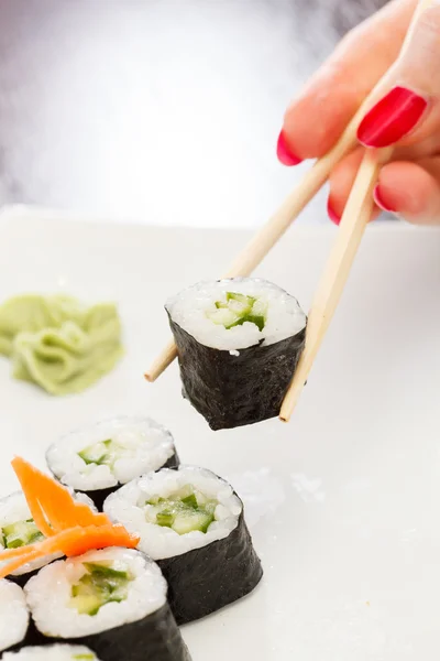 Mão com pauzinhos leva sushi — Fotografia de Stock