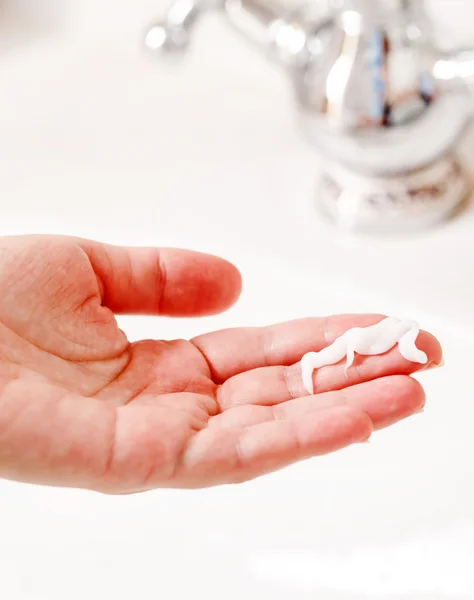 Hand with cream in bathroom — Stock Photo, Image