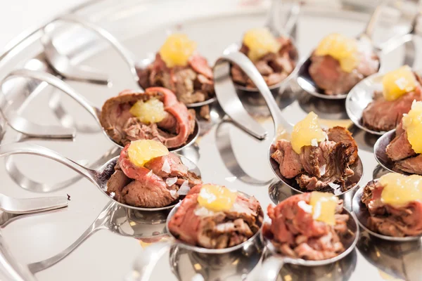 Canapes with meat on spoons — Stock Photo, Image
