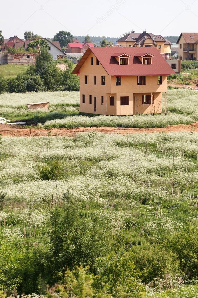Unfinished wooden house with red roof