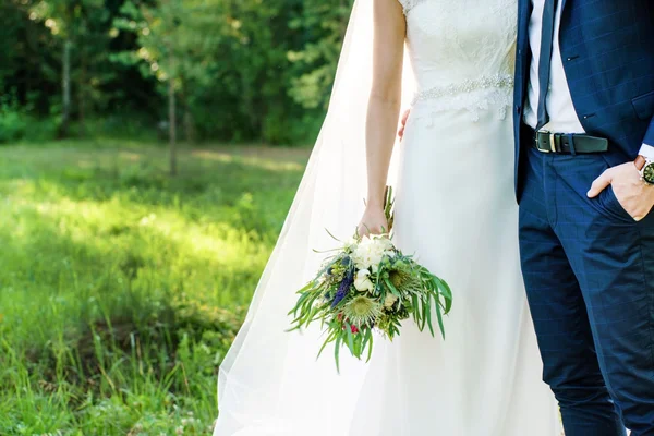 Brudgummen och bruden hålla blommor — Stockfoto