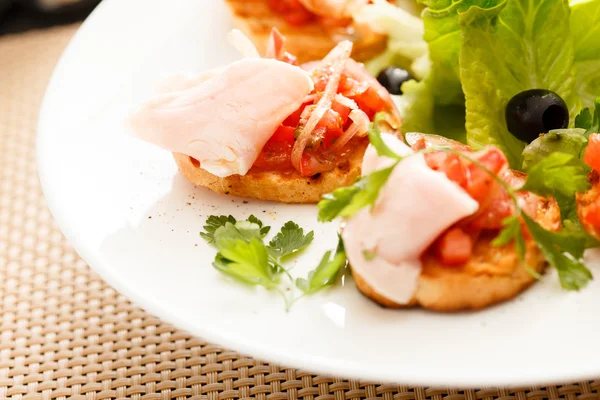 Tasty bruschettas with tomato and ham — Stock Photo, Image