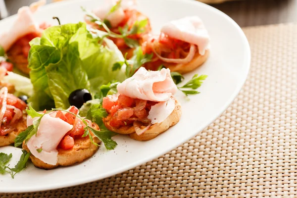 Bruschettas saborosas com tomate e presunto — Fotografia de Stock