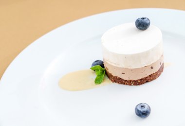 Tabağında yaban mersini olan peynirli kek.