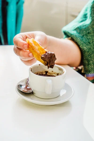 Eating tasty churros with chocolate — Stock Photo, Image