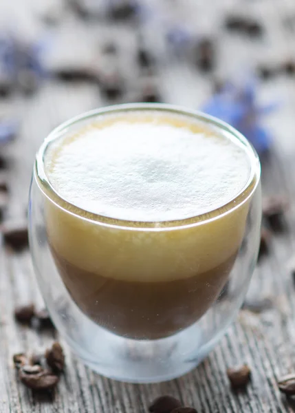 Copo com cappuccino e grãos de café — Fotografia de Stock
