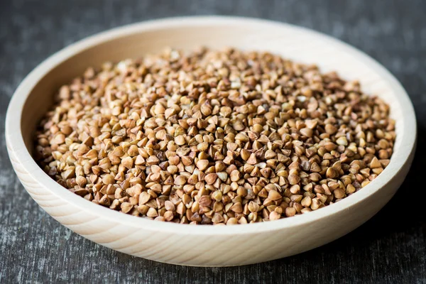 Raw buckwheat in wooden plate — Stock Photo, Image