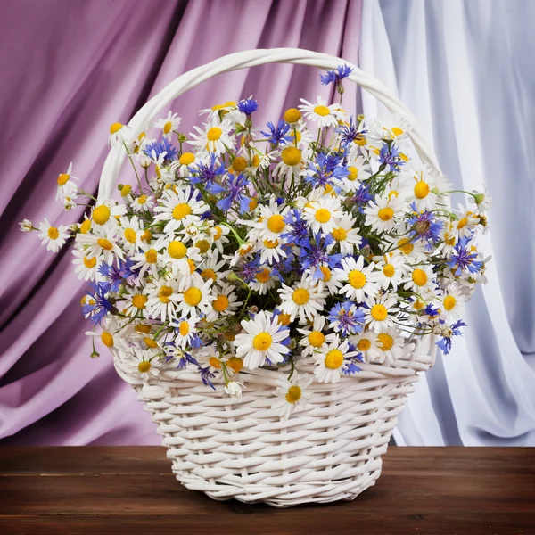 Gänseblümchen und Kornblumen im Korb — Stockfoto