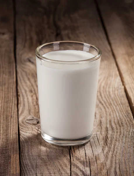 Свежее молоко в стакане на старых досках — стоковое фото