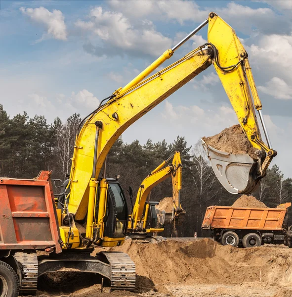 Excavadoras envían arena en camiones en construcción de carreteras —  Fotos de Stock