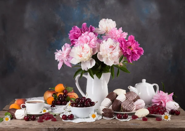 Todavía peonías y postre. caramelos, té, frutas, cerezas — Foto de Stock