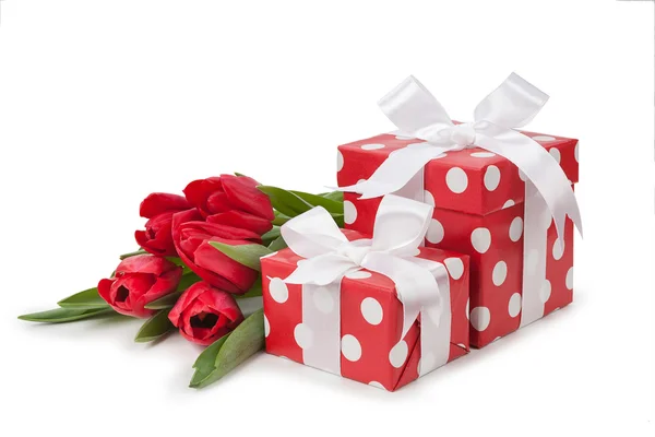 Red boxes with white ribbons and a bouquet of tulips — Stock Photo, Image