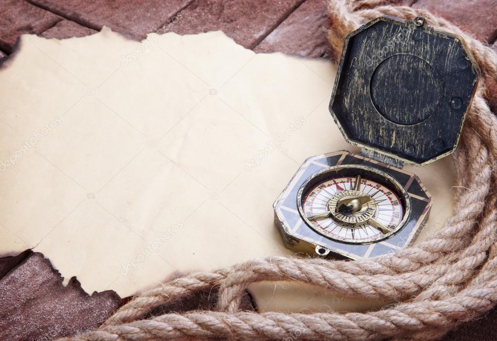 Vintage compass on the paper and marine ropes