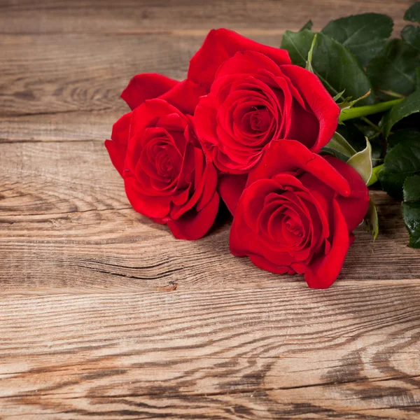 Belle rose rosse sulla vecchia tavola — Foto Stock