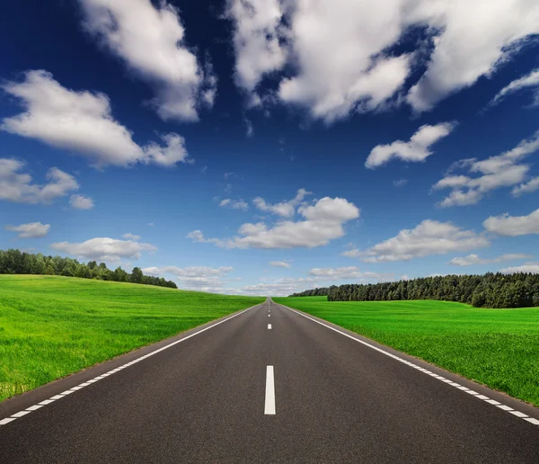 Camino bajo el hermoso cielo entre verdes colinas — Foto de Stock