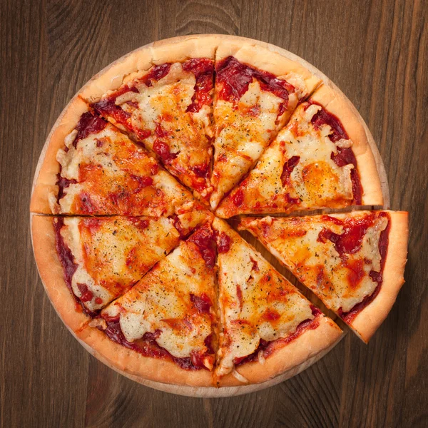 Sliced pizza Margherita on the old board — Stock Photo, Image