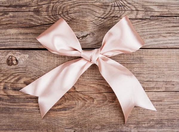 Pink bow lying on the old board — Stock fotografie