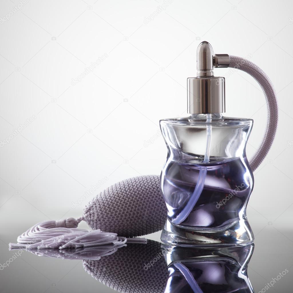Cosmetic spray perfume on a gray background with reflection