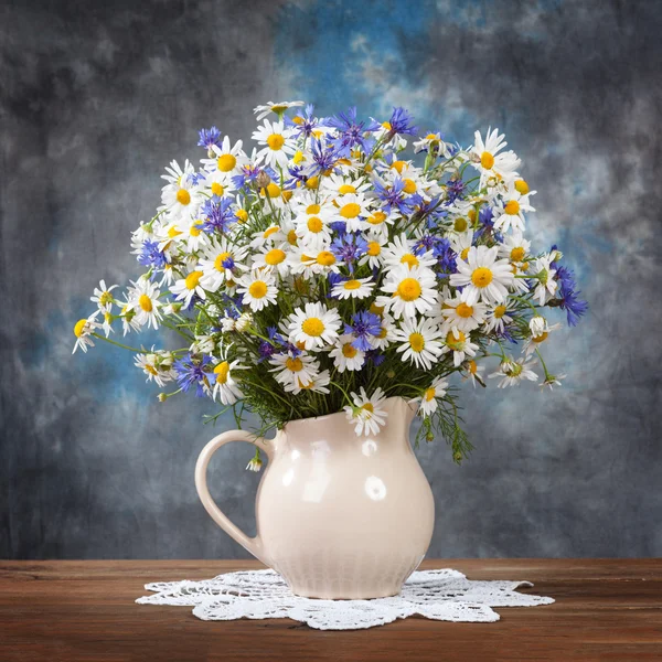 Kamille und Kornblumen in einem Korb auf dem Tisch — Stockfoto