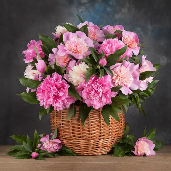 Bouquet peons in a basket on the table — Stock Photo, Image