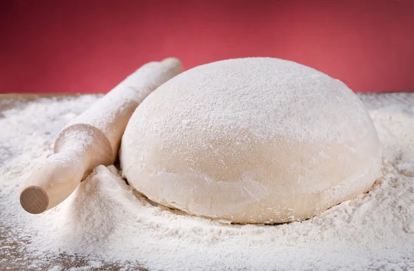 Wooden rolling pin with dough and flour — Stock Photo, Image