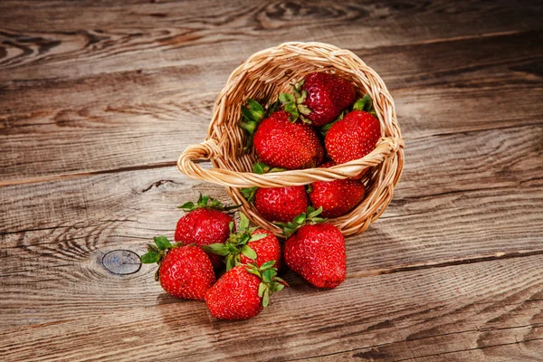 Strawberries in the basket poured into the old board — Zdjęcie stockowe