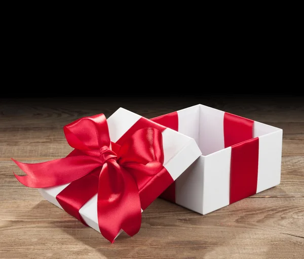White box with a red bow on old boards — Stock Photo, Image