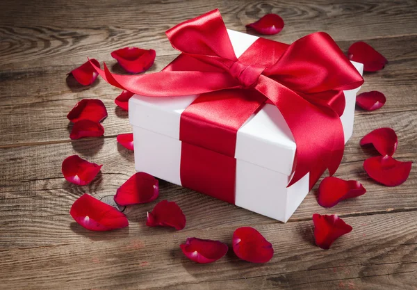 Gift box and rose petals on the old wooden boards — Stockfoto