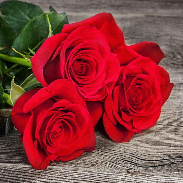 Bouquet di rose rosse sulle vecchie tavole — Foto Stock