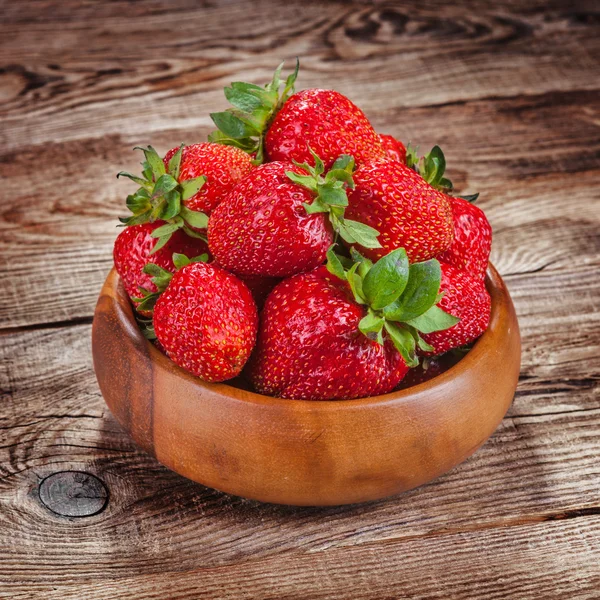 Strawberries in a bowl on old boards — Zdjęcie stockowe