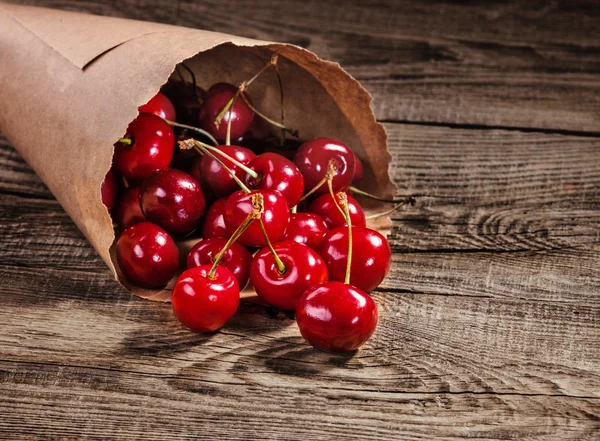 Zralé třešně v papírových taškách na starých desek — Stock fotografie