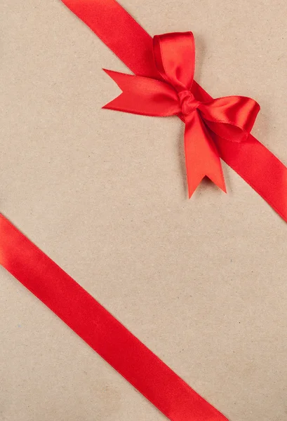 Концепція подарунка - Червоний лук і стрічка на картоні — стокове фото
