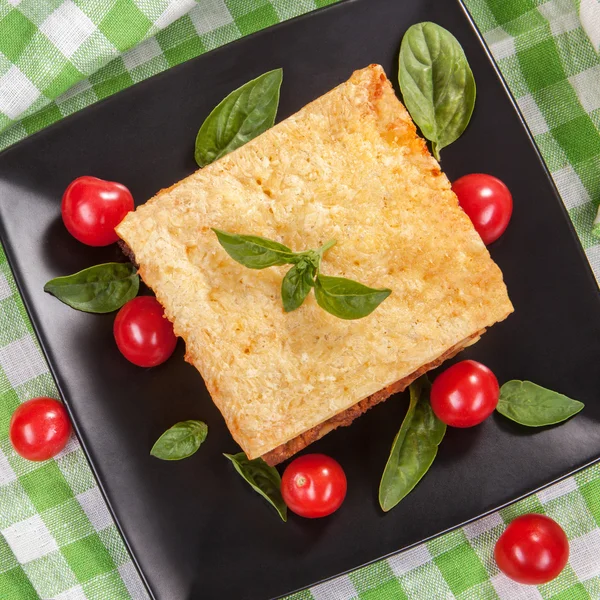 Tasty lasagna tomato and basil on a black square plate — Stock Photo, Image