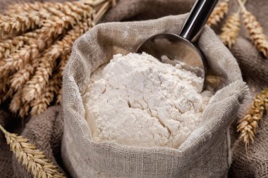 Flour in a bag on the table and spikelets clipart