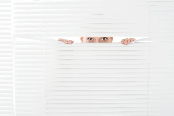 Young woman looks through jalousie — Stock Photo, Image