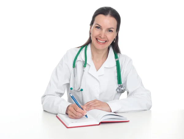 Junge Ärztin sitzt am Schreibtisch und lächelt — Stockfoto