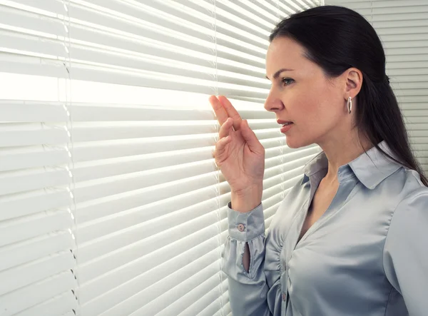 Femme regarde par la fenêtre du bureau — Photo