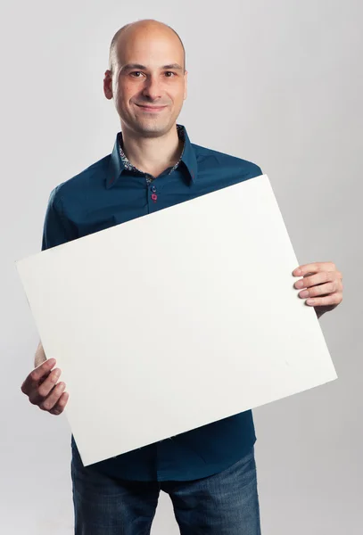 Bonito sorrindo careca homem apresentando folha de papel vazia Imagem De Stock