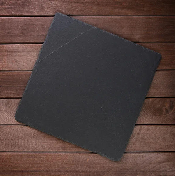 Placa de ardósia de pedra no fundo de madeira rústico — Fotografia de Stock