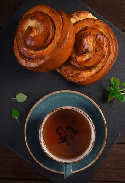 Top view of sweet buns with cup of tea — Stock Photo, Image