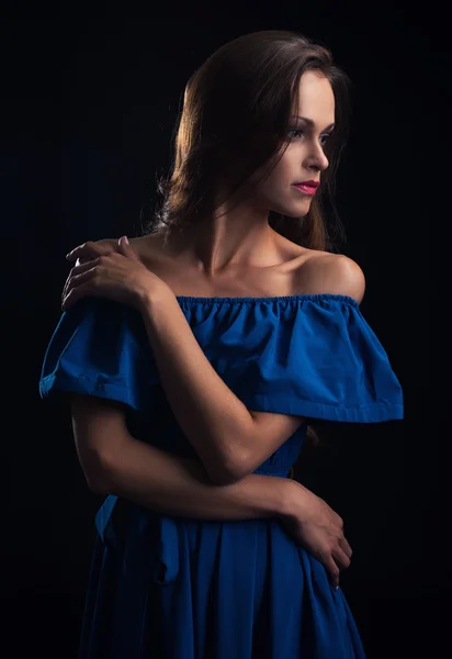 Bela mulher vestindo vestido azul no fundo preto — Fotografia de Stock