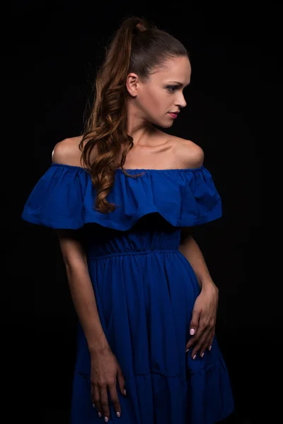 Hermosa mujer vistiendo vestido azul sobre fondo negro — Foto de Stock