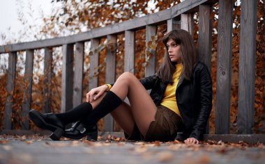 Esmer kadın sonbahar parkında oturuyor.